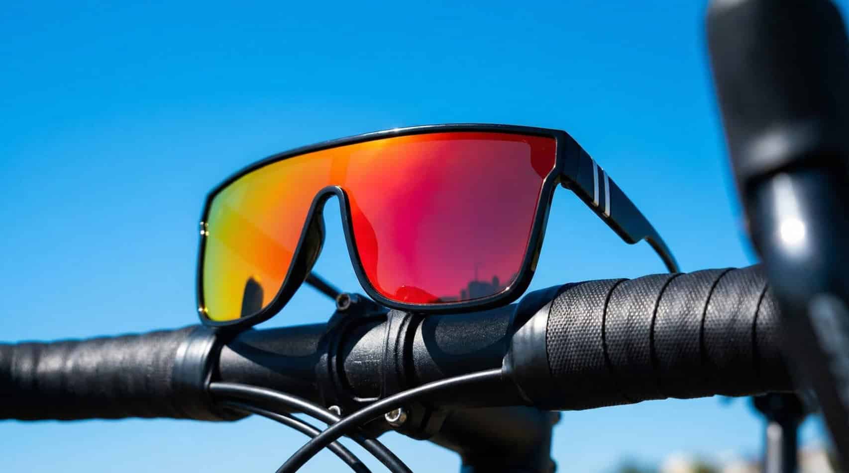 Professional testing setup showing multiple cycling glasses arranged on a cycling workbench with testing equipment and outdoor gear